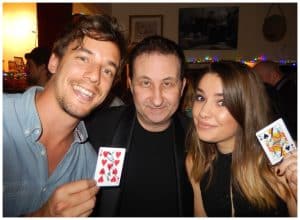 Andy Field performing close-up magic for a man and woman holding playing cards at an event in Swindon