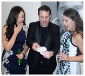 Andy Field performing a card trick for two amazed women capturing a moment of wonder during mix and mingle close up magic