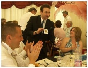 Bath magician performing close-up magic at a table while guests applaud