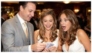 Two women watch a magician make an object disappear during a close-up magic trick